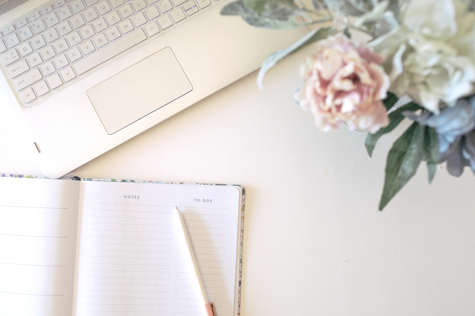 Girl boss working space with laptop, flowers and journal